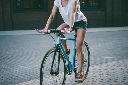 Young beautiful girl rides her single speed of fixed gear bicycle in the city. Toned pictureの写真素材