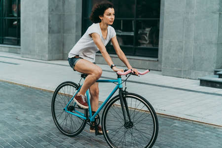 Young beautiful girl rides her single speed of fixed gear bicycle in the city.