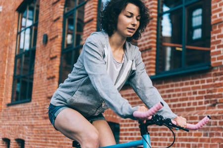 Young beautiful girl rides her single speed of fixed gear bicycle in the city.の写真素材