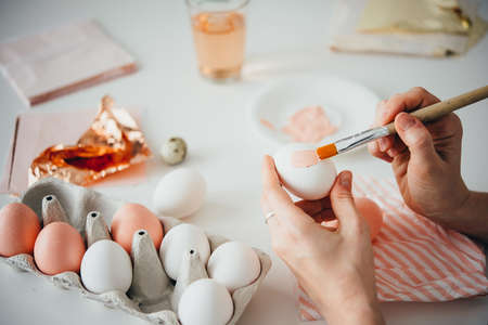 Hands painting modern style easter eggs with pink paintの写真素材