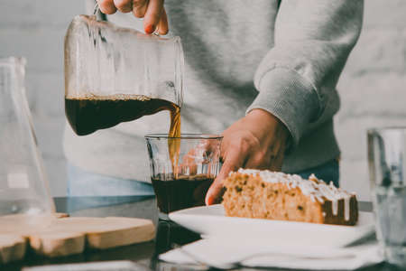 Girl pouring coffee in a glass and dessert on a cafe table. Toned imageの写真素材