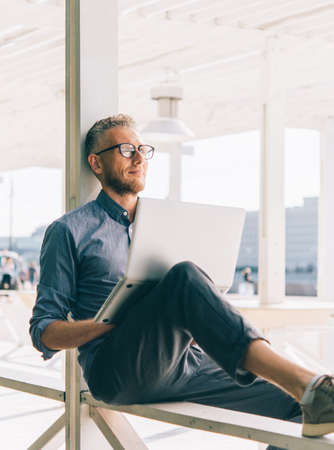 Mature handsome man relaxing outside and working on his laptop.