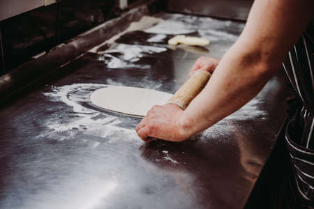 Chef is making pizza dough on the metal kitchen table.の写真素材