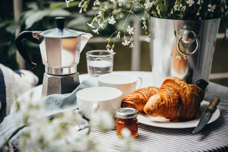 Breakfast with croissants and coffee served on a beautiful terrace or balconyの写真素材