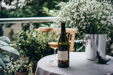 Wine bottle, glass and flowers on a beautiful terrace or balconyの写真素材