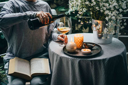 Girl pouring wine on a terrace. Cozy evening and relax concept