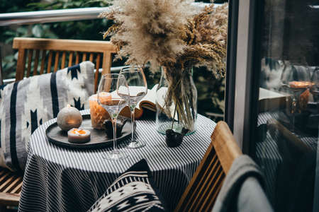 Beautiful terrace or balcony with candles, wine glasses and book on a tableの写真素材