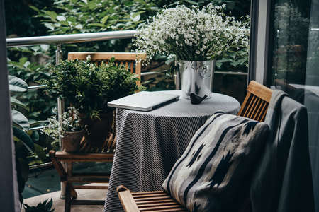 Beautiful terrace or balcony with small table, laptop and flowersの写真素材