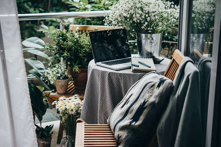 Beautiful terrace or balcony with small table, laptop and flowersの写真素材