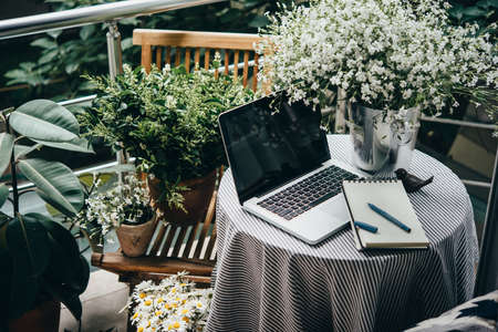 Beautiful terrace or balcony with small table, laptop and flowersの写真素材
