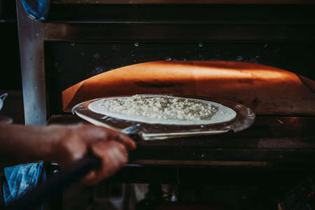 Chef is putting pizza in the oven.の写真素材