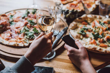 Various pizzas and glasses of wine served for dinner in a restaurant.の写真素材