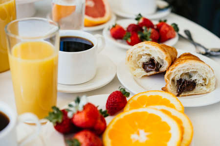 Healthy breakfast served with black coffee, croissant, orange juice and fruitsの写真素材