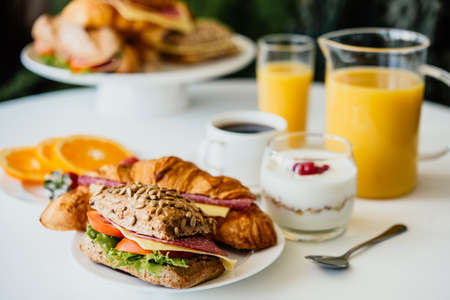 Healthy breakfast served with black coffee, sandwiches, muesli and orange juiceの写真素材