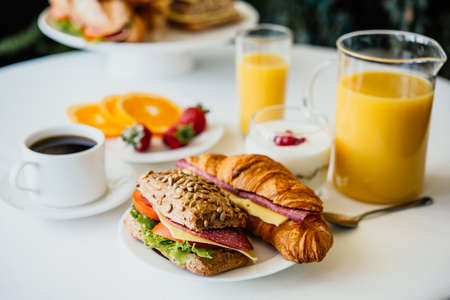 Healthy breakfast served with black coffee, sandwiches, muesli and orange juiceの写真素材
