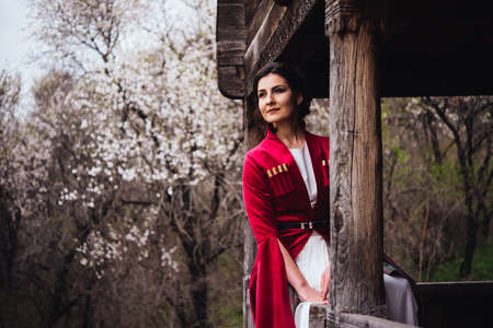 Portrait of a young beautiful girl wearing traditional georgian dress sitting on the porch.の写真素材