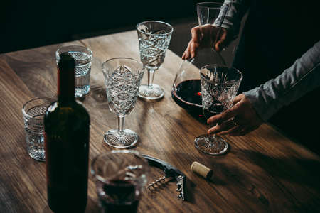 Pouring red wine from decanter onto glassesの写真素材