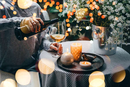 Girl pouring wine on a terrace. Cozy evening and relax conceptの写真素材