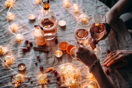 Friends celebrating Christmas or New Year eve. Party table with rose champagne.