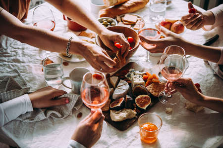 Friends having a dinner party with different kinds of appetizers and rose wine.の写真素材