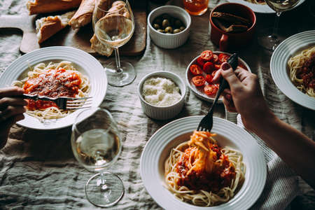 Friends having a pasta dinner at home of at a restaurant.の写真素材