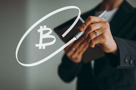 Writing hand. Business woman holds pen or marker and writing Bitcoin symbolの写真素材