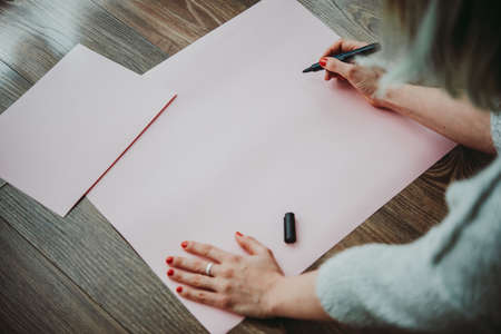 Young woman writing something on a big piece of paperの写真素材