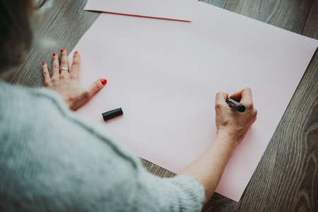 Young woman writing something on a big piece of paperの写真素材