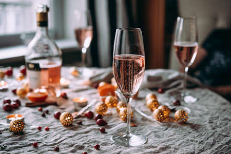 Friends celebrating Christmas or New Year eve. Party table with rose champagne.の写真素材