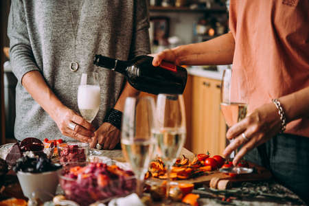 Pouring champagne at a dinner party with friends. Dinner table, celebrating Christmas or New Year eve.の写真素材