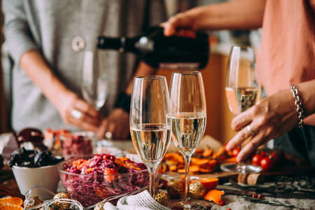 Pouring champagne at a dinner party with friends. Dinner table, celebrating Christmas or New Year eve.の写真素材