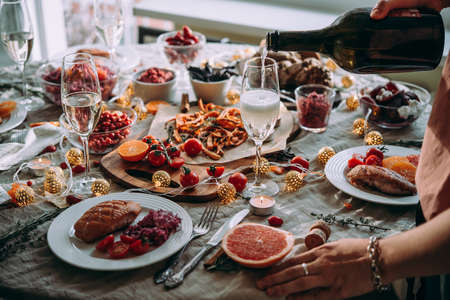 Pouring wine at a dinner party with friends. Friends celebrating Christmas or New Year eve.の写真素材