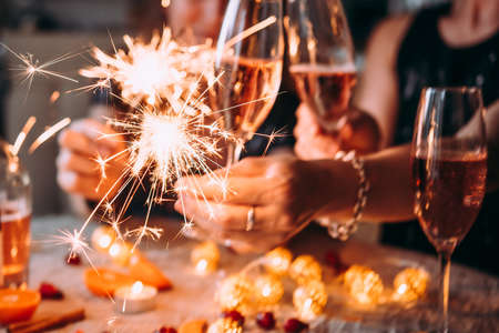 Friends celebrating Christmas or New Year eve party with Bengal lights and rose champagne.の写真素材