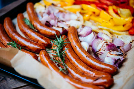 A tray with baked sausages and vegetablesの写真素材