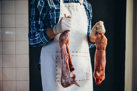 Butcher holds rabbit whole rounds.