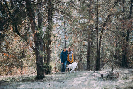 Happy lesbian couple walking in the forest with a dogの写真素材