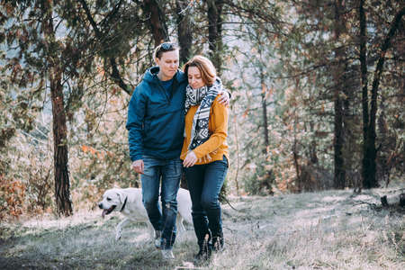 Happy lesbian couple walking in the forest with a dogの写真素材