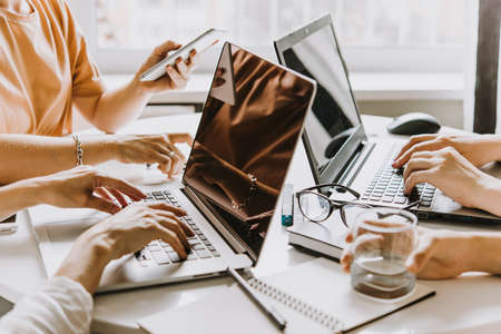Laptops, mobile phones and notebooks on a working table in creative office. Successful teamwork and business startup concept.の写真素材