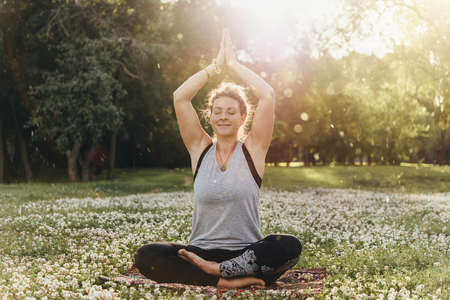 A young beautiful woman is meditating or practising yoga outdoors. Outdoor recreation concept.の写真素材
