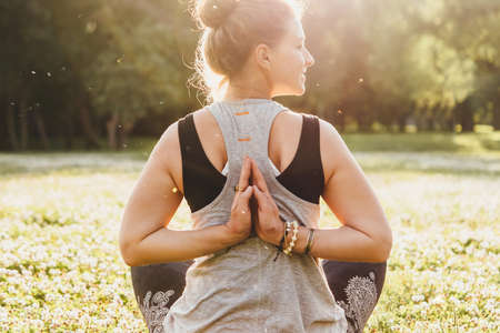 A young beautiful woman is meditating or practising yoga outdoors. Outdoor recreation concept.の写真素材