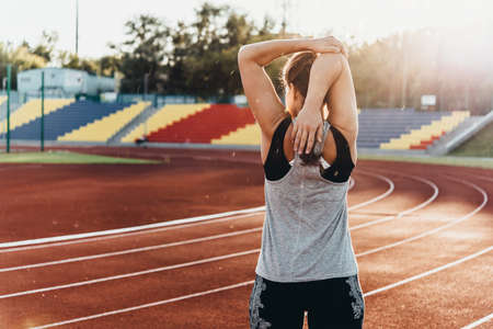 A young beautiful woman is warming up before jogging of exercising at a stadium running track.の写真素材