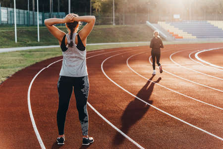 A young beautiful woman is warming up before jogging of exercising at a stadium running track.の写真素材