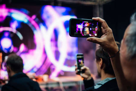 A person taking photo or video with his smartphone during a concert or a performance.