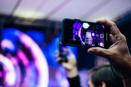 A person taking photo or video with his smartphone during a concert or a performance.の写真素材