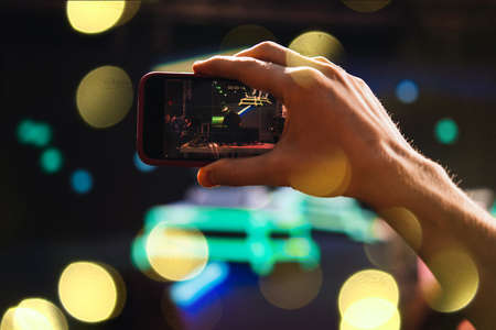 A person taking photo or video with his smartphone during a concert or a performance.の写真素材