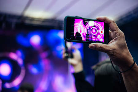 A person taking photo or video with his smartphone during a concert or a performance.の写真素材