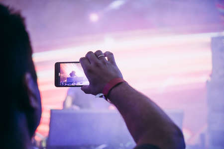 A person taking photo or video with his smartphone during a concert or a performance.の写真素材