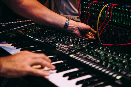 Playing music using an analog synthesizer connected to a modular synthesizer. Electronic music and professional music equipment concept.の写真素材