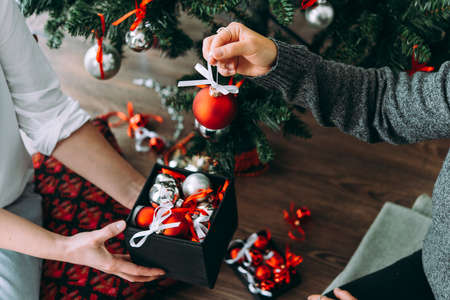 Friends or family decorating a Christmas tree. Christmas and New Year celebration concept.の写真素材