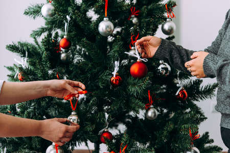 Friends or family decorating a Christmas tree. Christmas and New Year celebration concept.の写真素材